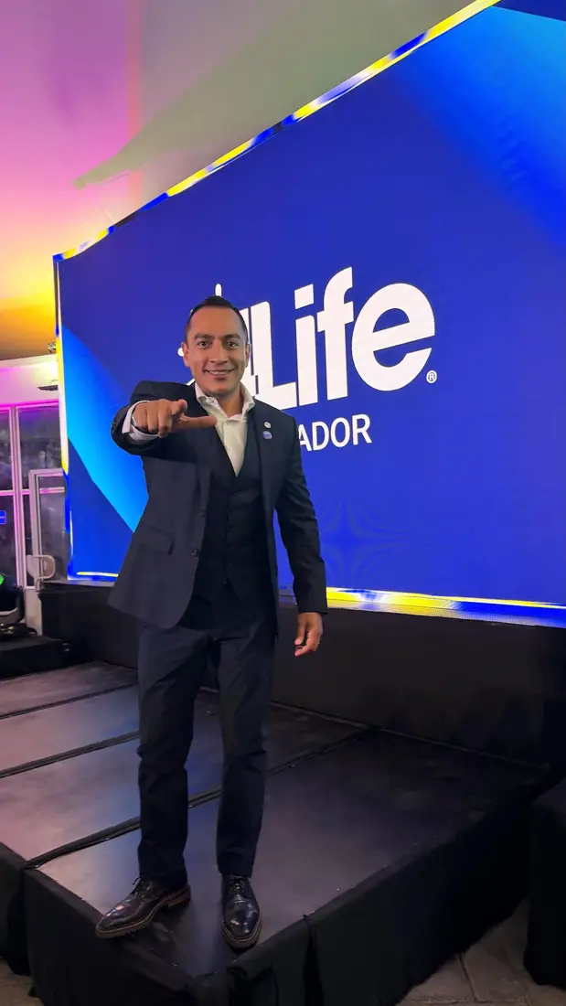 Rafa el Networker en escenario 4Life Ecuador señalando al público con traje formal